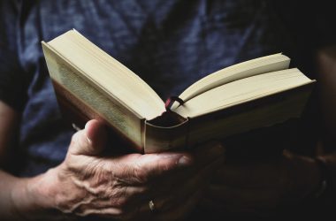 Close-up of hands holding a best fantasy books of all time, perhaps authors like Joe Abercrombie, with pages slightly fanned out