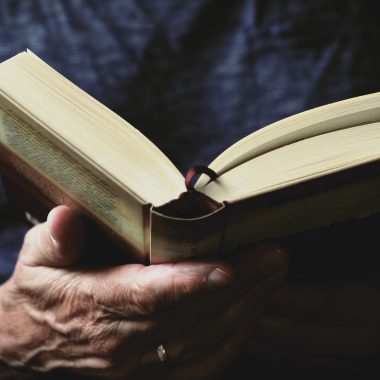 Close-up of hands holding a best fantasy books of all time, perhaps authors like Joe Abercrombie, with pages slightly fanned out