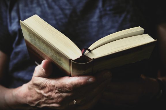 Close-up of hands holding a best fantasy books of all time, perhaps authors like Joe Abercrombie, with pages slightly fanned out