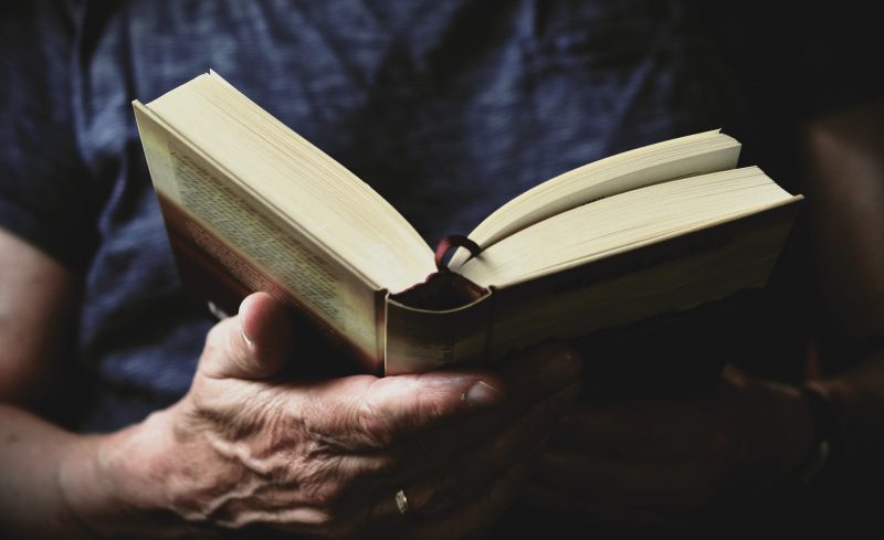 Close-up of hands holding a best fantasy books of all time, perhaps authors like Joe Abercrombie, with pages slightly fanned out