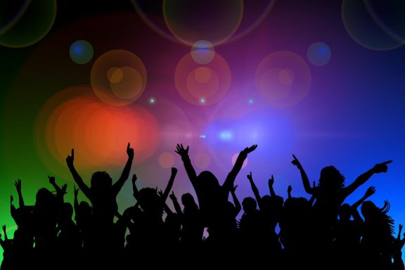 An image of silhouettes partying under colorful lights.