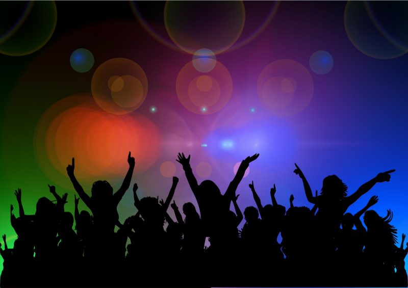 An image of silhouettes partying under colorful lights.